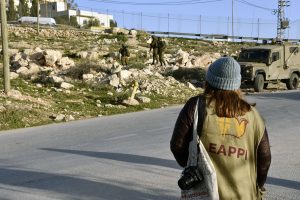 EAPPI-tarkkailija katsoo, kun kolme israelilaista sotilasta on noussut pakettiautostaan tien sivuun.