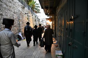 Vanhoillisia juutalaisia miehiä ja musliminainen kävelee vanhan kaupungin katua.