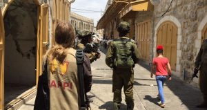 EAPPI-tarkkailija seuraa sotilaita ja lasta Hebronin vanhan kaupungin autiokadulla.